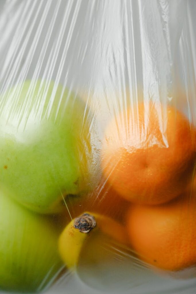 Colorful citrus fruits like oranges and apples in a plastic bag, highlighting eco-awareness.